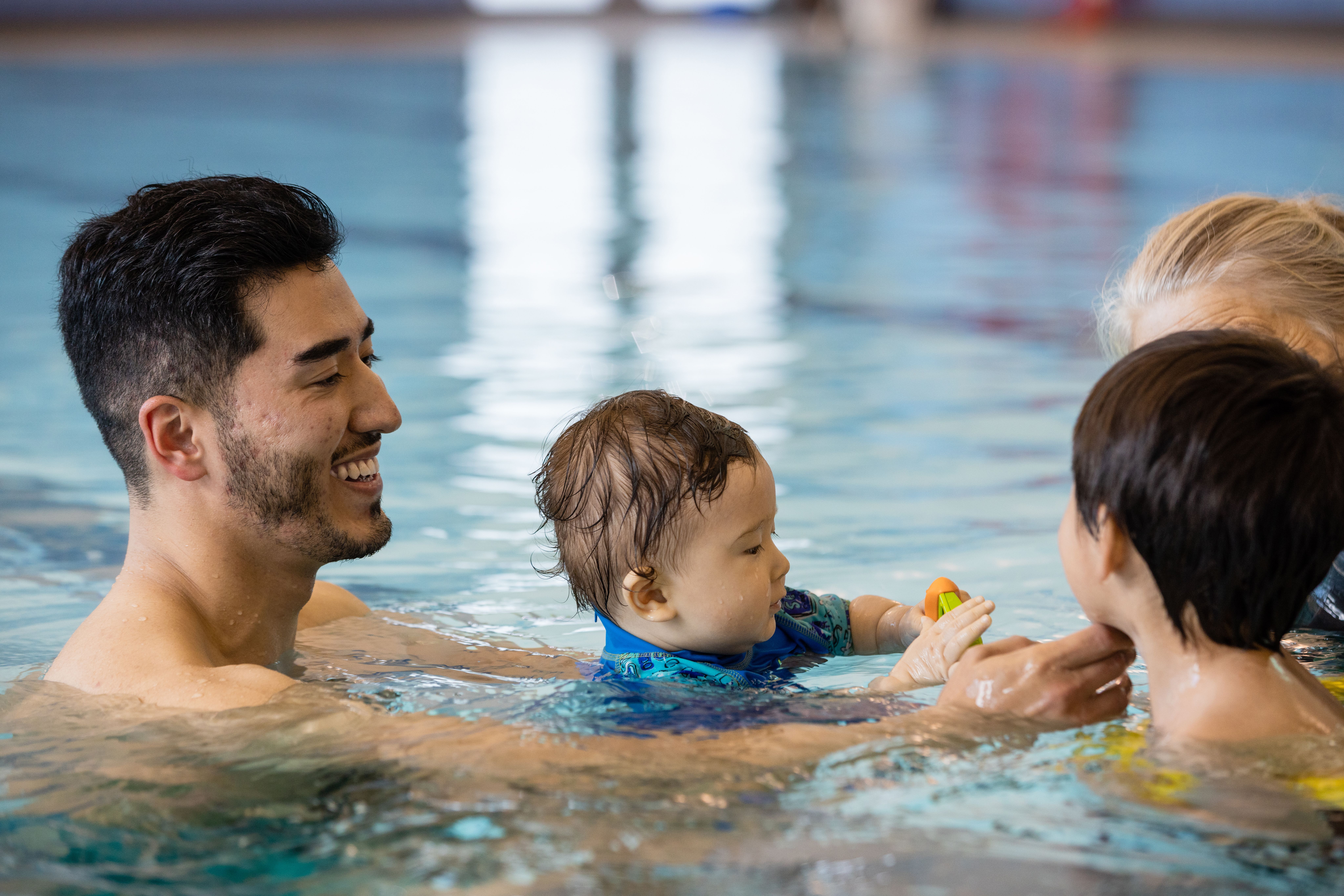 Mom and dad swimming with two kids in pool