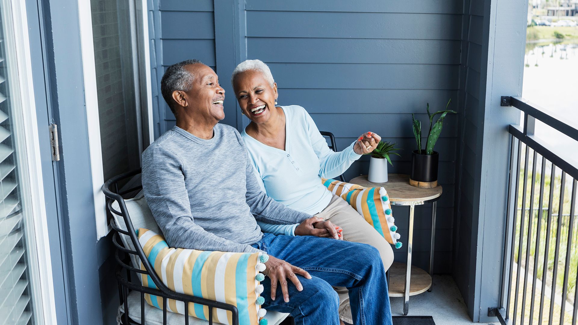 Older couple sitting on bench talking while looking out over balcony