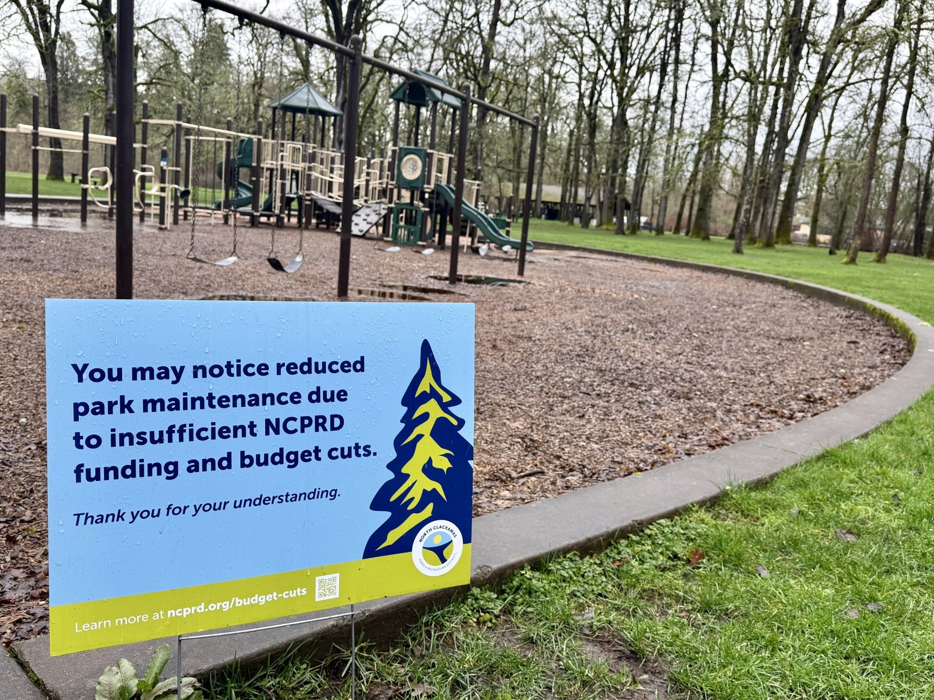 Budget reduction yard sign in park in front of playground